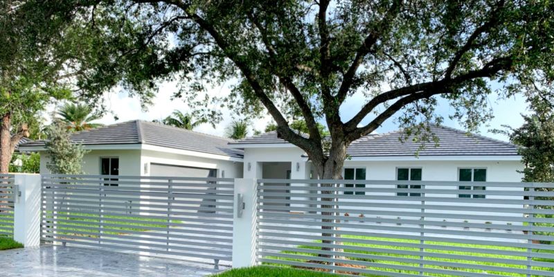Street view of completed home with horizontal aluminum fence and gate