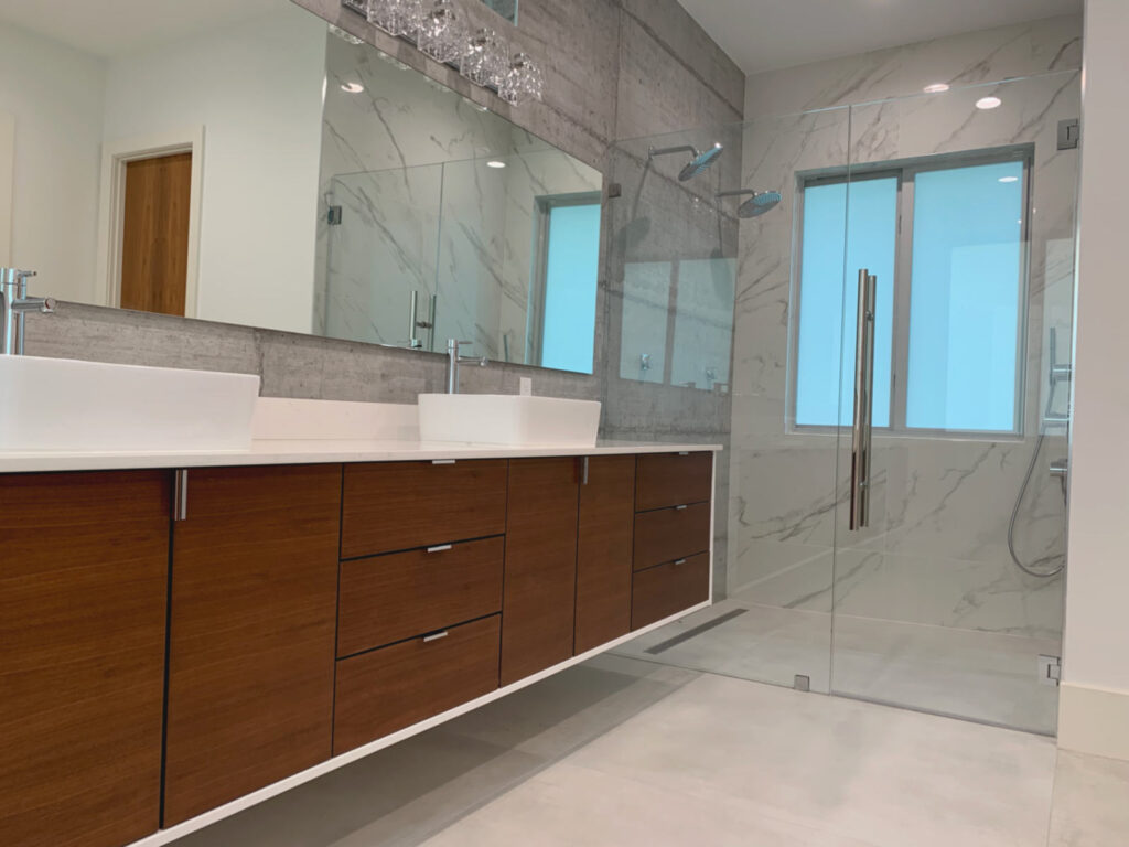 Closeup of dual vanity in primary bathroom with glass shower enclosure in the background