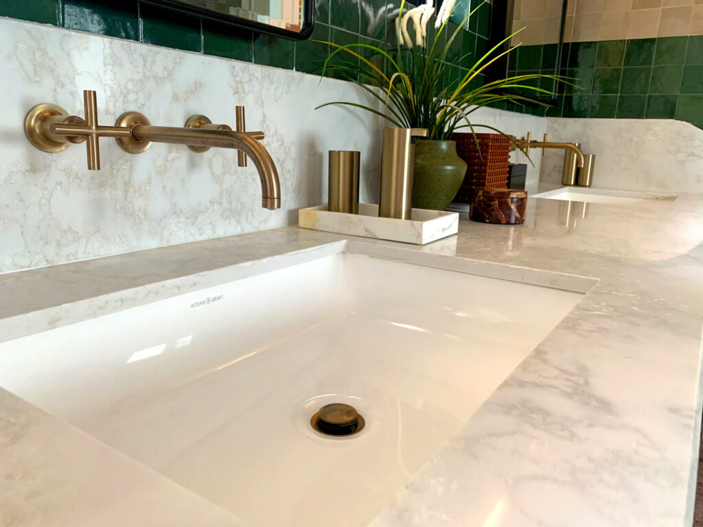 Closeup of dual vanity with marble countertop and brass taps