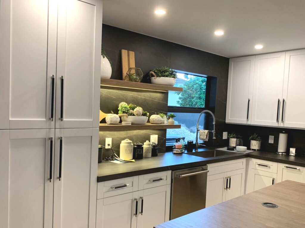 Perimeter shaker cabinets, black porcelain countertop and floating shelves with downcast LED lighting