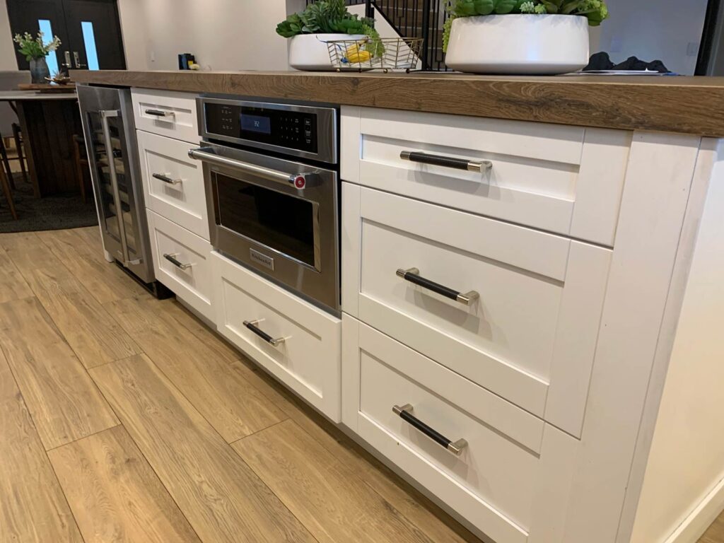 White shaker cabinets, wood-grain porcelain countertop and microwave on center island