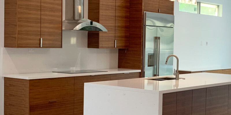 Wide view of wood-grain cabinets and quartz countertop with waterfall edge